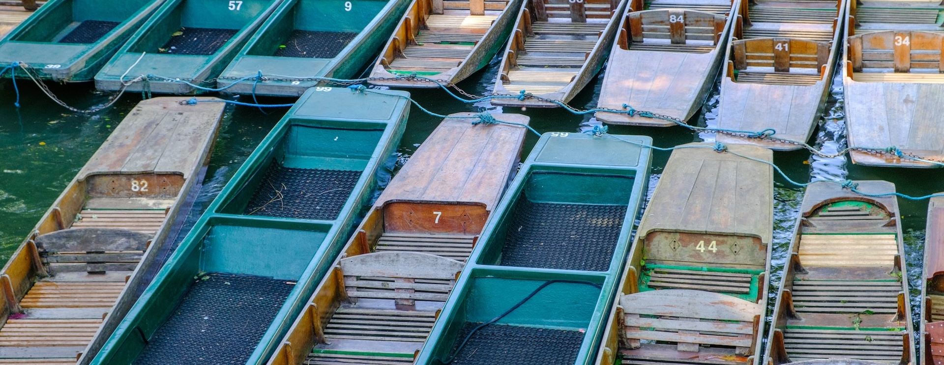 A group of around 12 different coloured narrow boats sitting on the water.