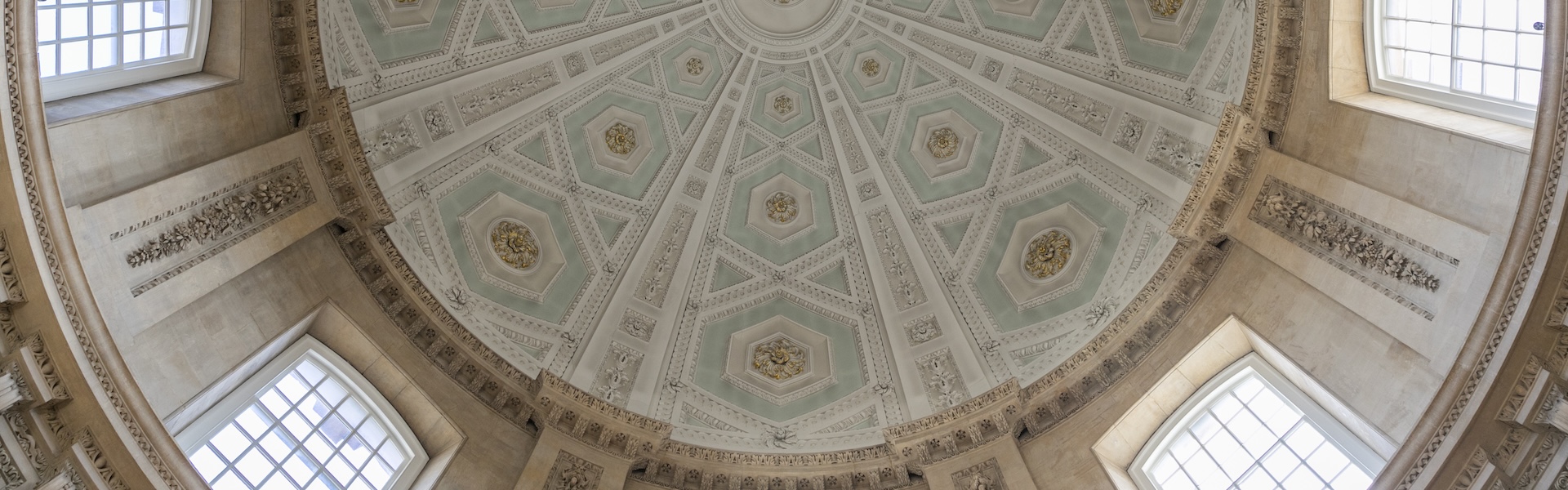 Interior ceiling of a beautiful domed building with intricate pale blue and gold designs.