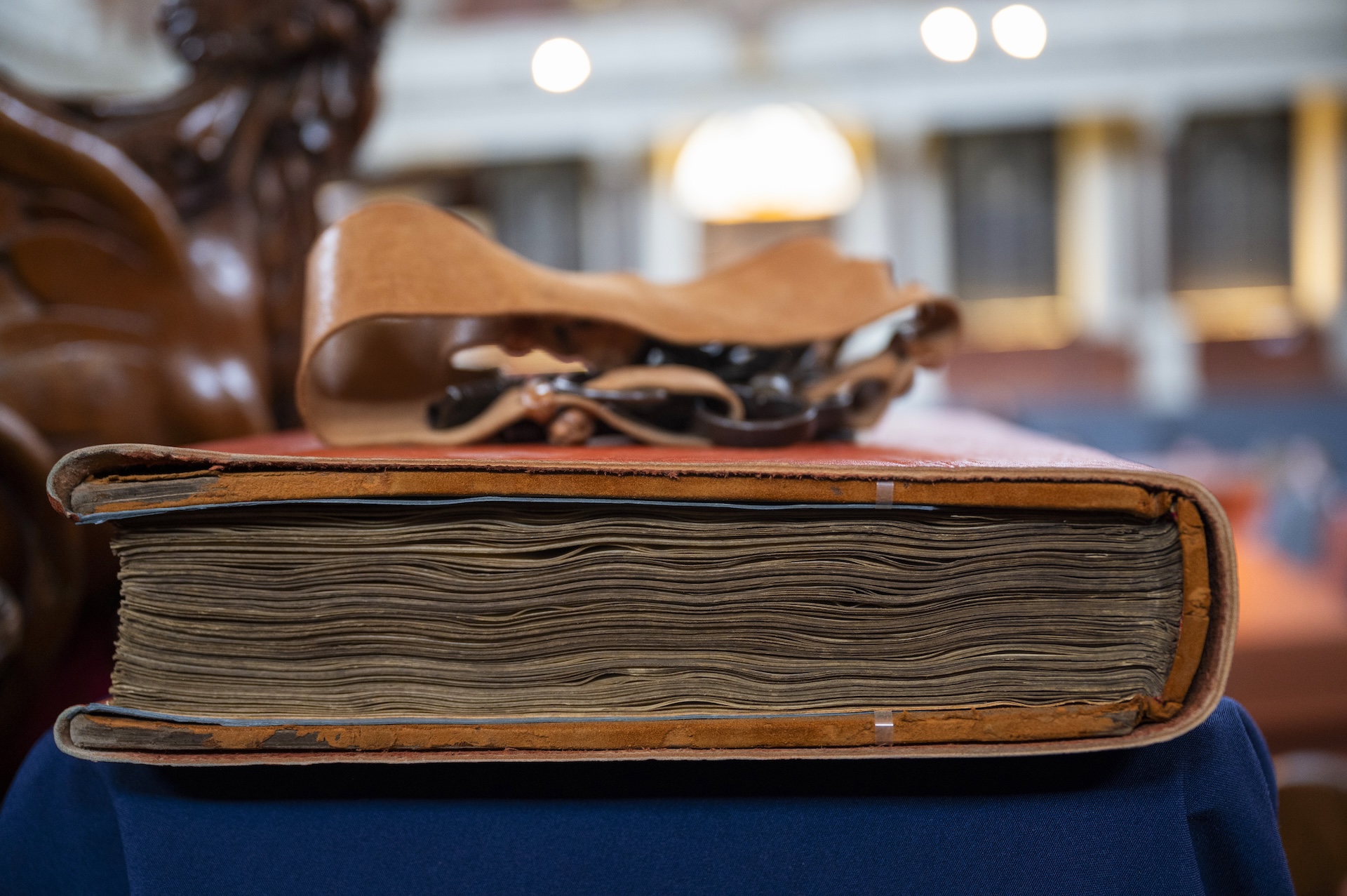 Side view of a thick historical brown leather bound book.