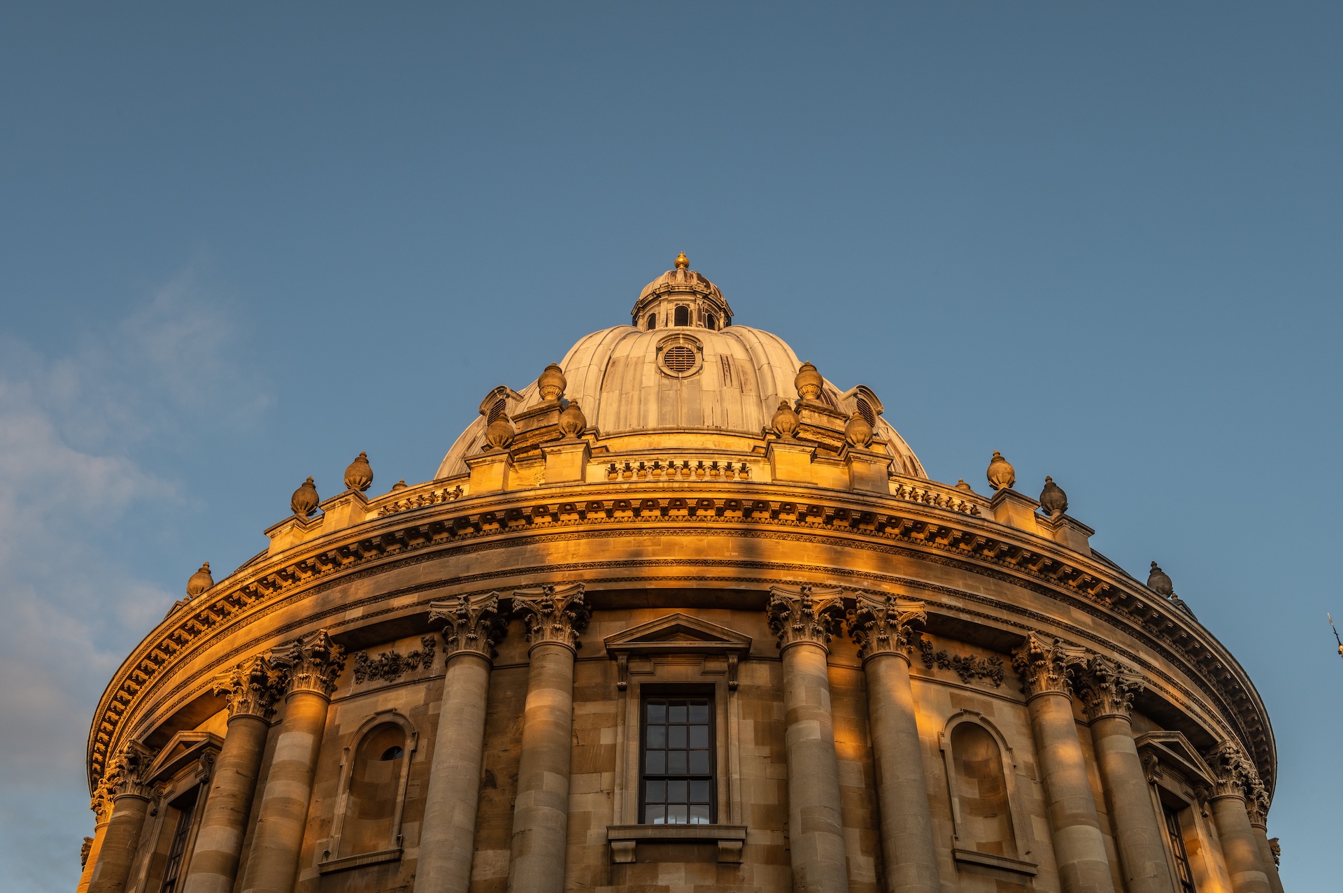 Circular historical stone building with a bright blue sky above.