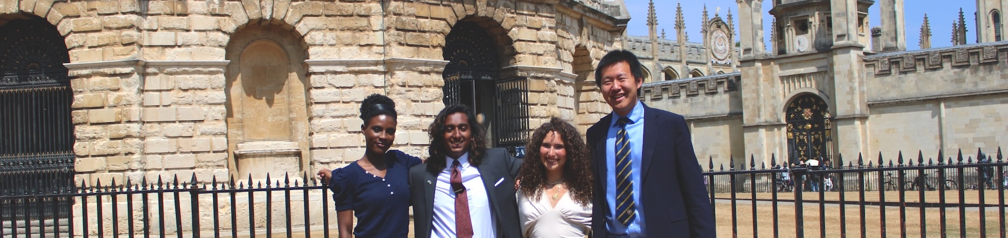 Group shot of four people stood in front of a historical circular Oxford stone building.